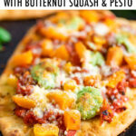 Naan pizza topped with tomatoes, butternut squash, pesto, and cheese.