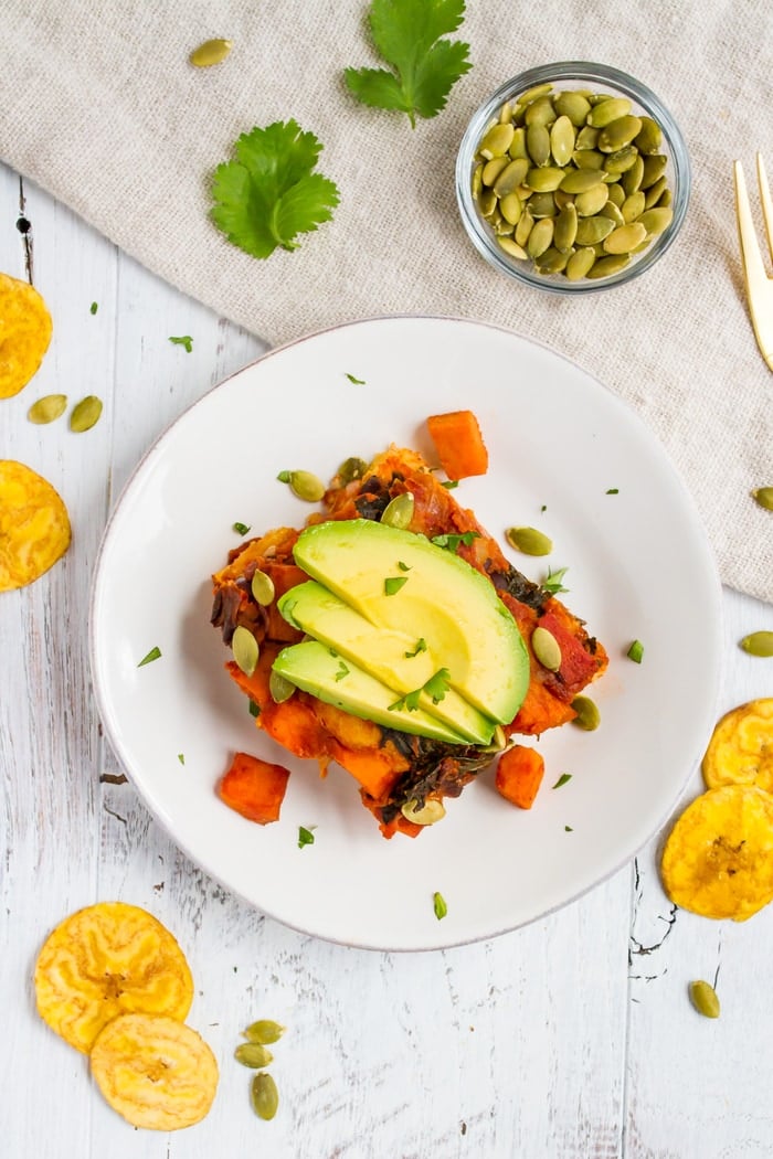 Overhead shot of Mayan harvest bake on a white plate with plantain chips scattered around.