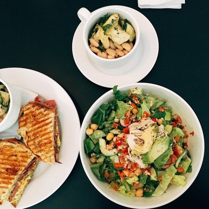 An overhead shot of lunch at Union Market. A bowl of salad and a plate with a sandwich cut in half. There is also a small bowl of soup.