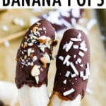 Two frozen bananas on a stick covered in chocolate and sprinkled with chopped almonds and coconut flakes.