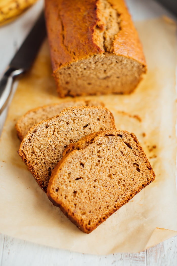 Whole wheat healthy banana bread loaf with three slices cut in front. Whole wheat healthy banana bread loaf with three slices cut in front.
