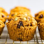 Pumpkin bran muffins stuffed with pumpkin seeds and raisins on a cooling rack.