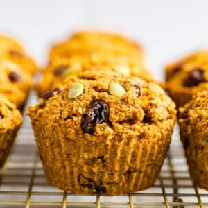 Pumpkin bran muffins stuffed with pumpkin seeds and raisins on a cooling rack.