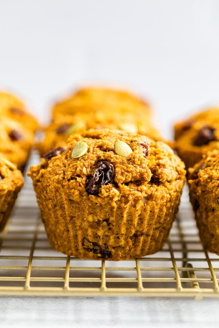 Pumpkin bran muffins stuffed with pumpkin seeds and raisins on a cooling rack.