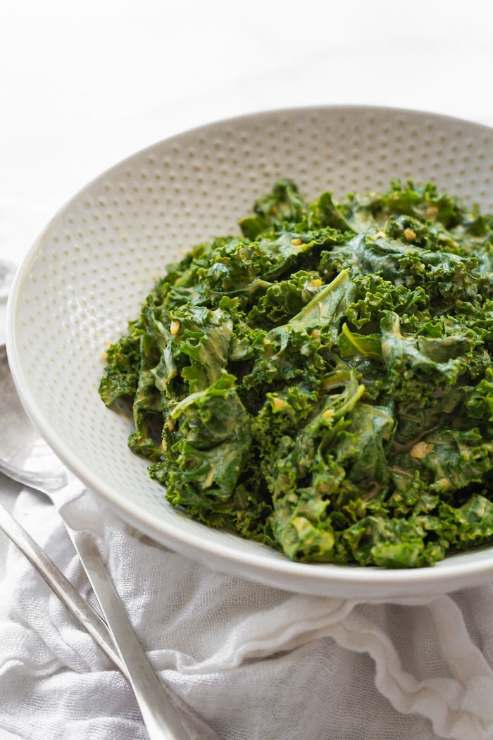 Side view of white bowl with garlicky kale salad.