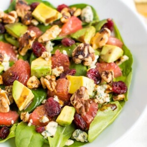 A shallow bowl filled with grapefruit avocado salad with arugula.