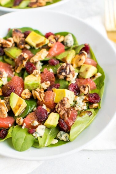 A shallow bowl filled with grapefruit avocado salad with arugula.