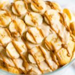 Peanut butter banana pudding topped with slices of bananas and a drizzle of peanut butter.