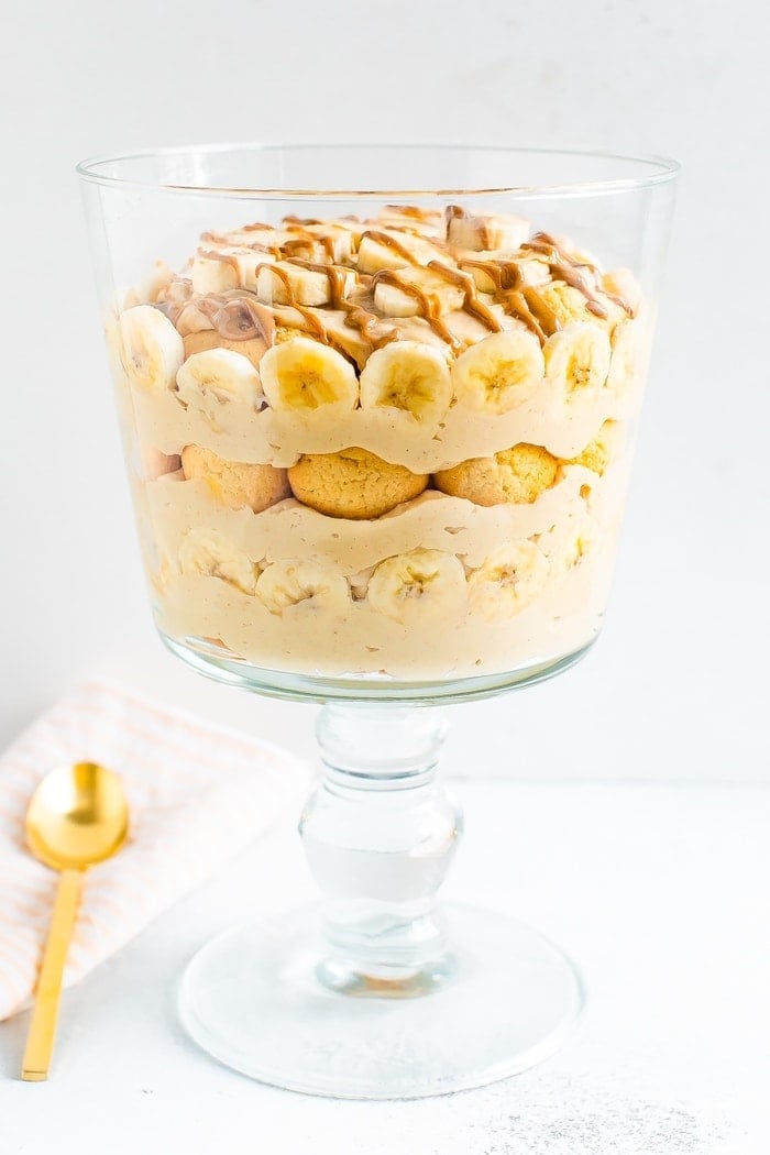 Trifle glass with layers of peanut butter pudding, banana slices, vanilla wafers and a drizzle of peanut butter.