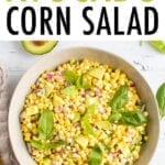 bowl of raw corn and avocado salad topped with fresh basil leaves.