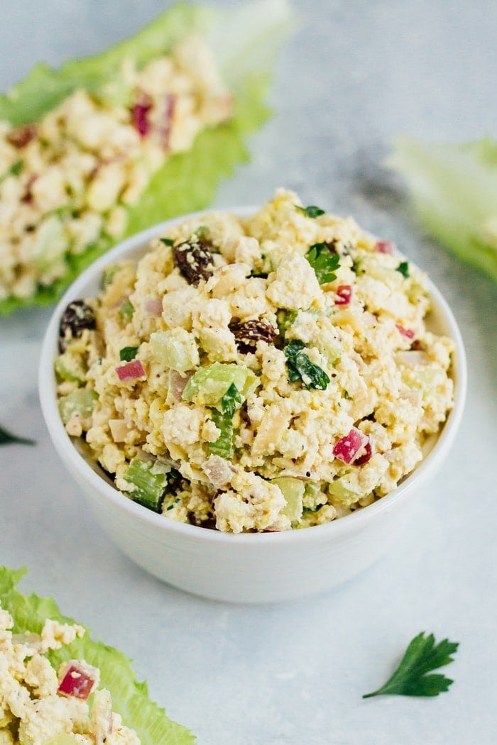 Vegan Chicken Salad made with tofu, celery, almonds and raisins in a white bowl on white countertop.