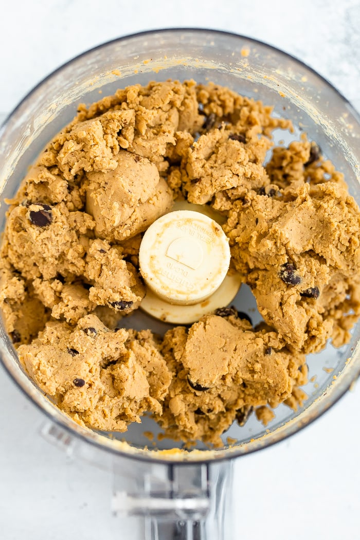 Food processor with healthy chickpea chocolate chip cookie dough blended together.