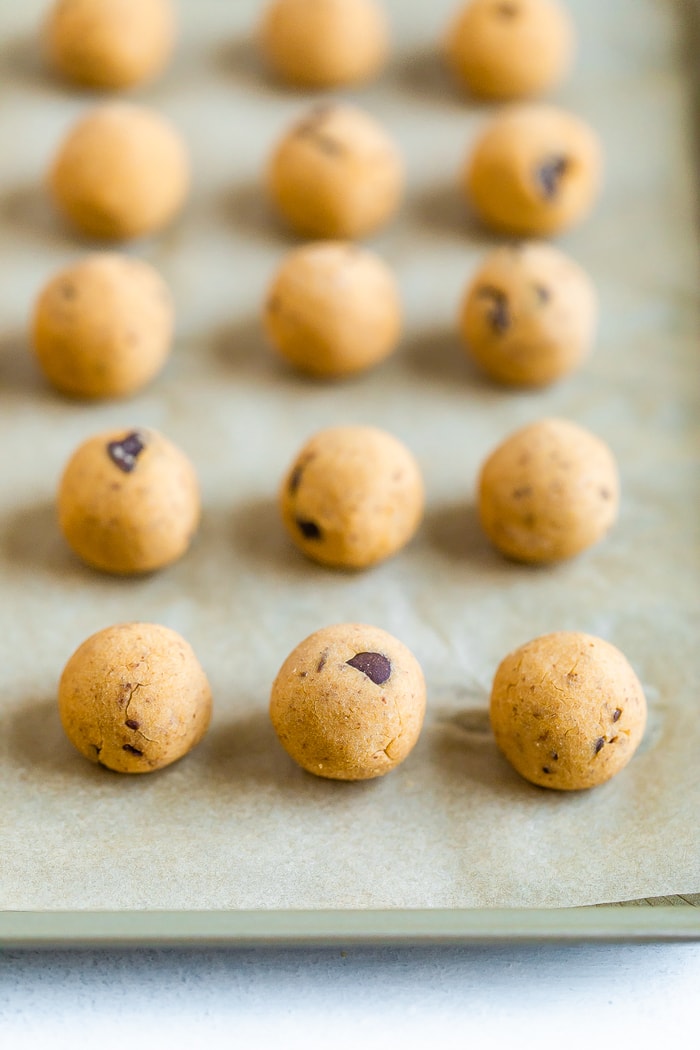 Chickpea cookie dough rolled into balls on parchment paper.