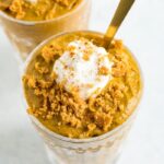 Two glasses of pumpkin chia mousse topped with greek yogurt and graham cracker crumbs.