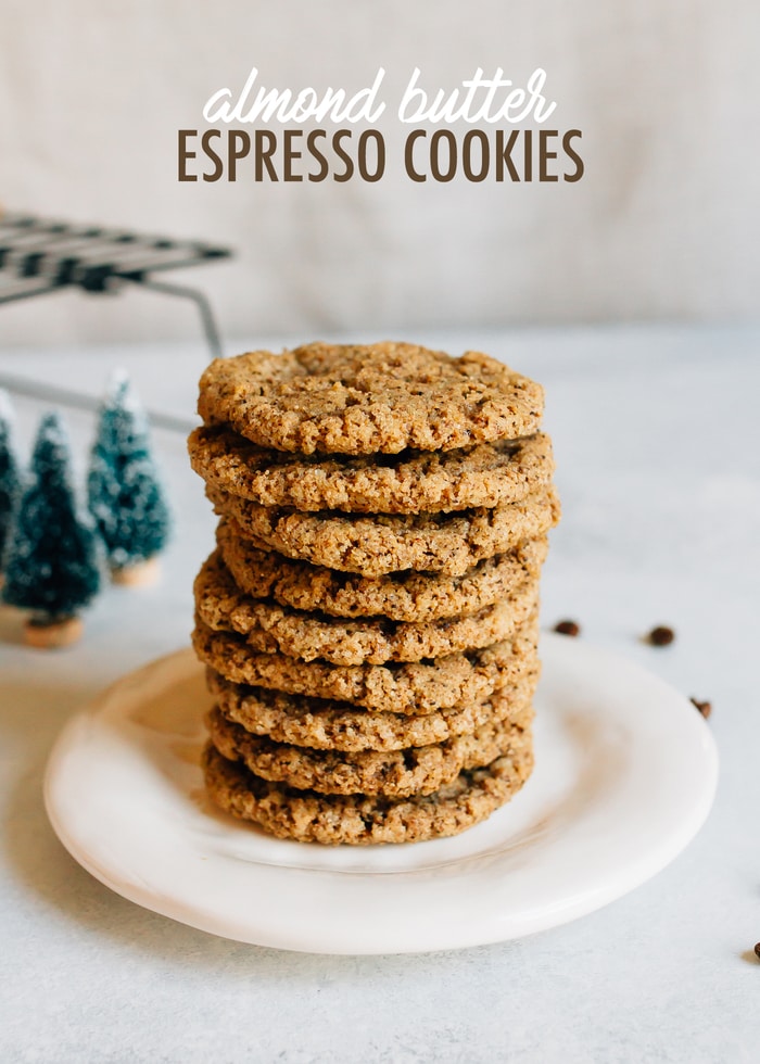 Stack of almond butter expresso cookies. Mini Christmas trees and a cooling rack in the background.