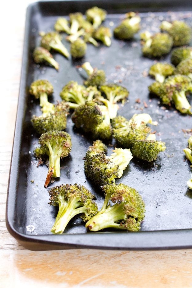 Sheet pan with broccoli and garlic spread around.