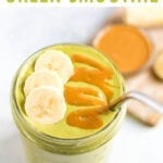 Green smoothie in a mason jar, topped with banana slices and a peanut butter drizzle. A metal straw is in the jar.