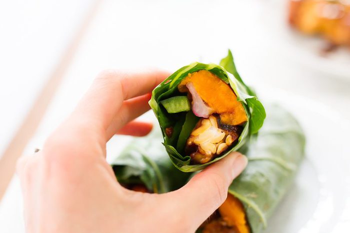 Delicious tempeh collard wraps with creamy hummus, slices of baked sweet potato, green pepper, red onion and cranberries.