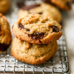 Stack of a couple chocolate chip cookies on a wire rack.