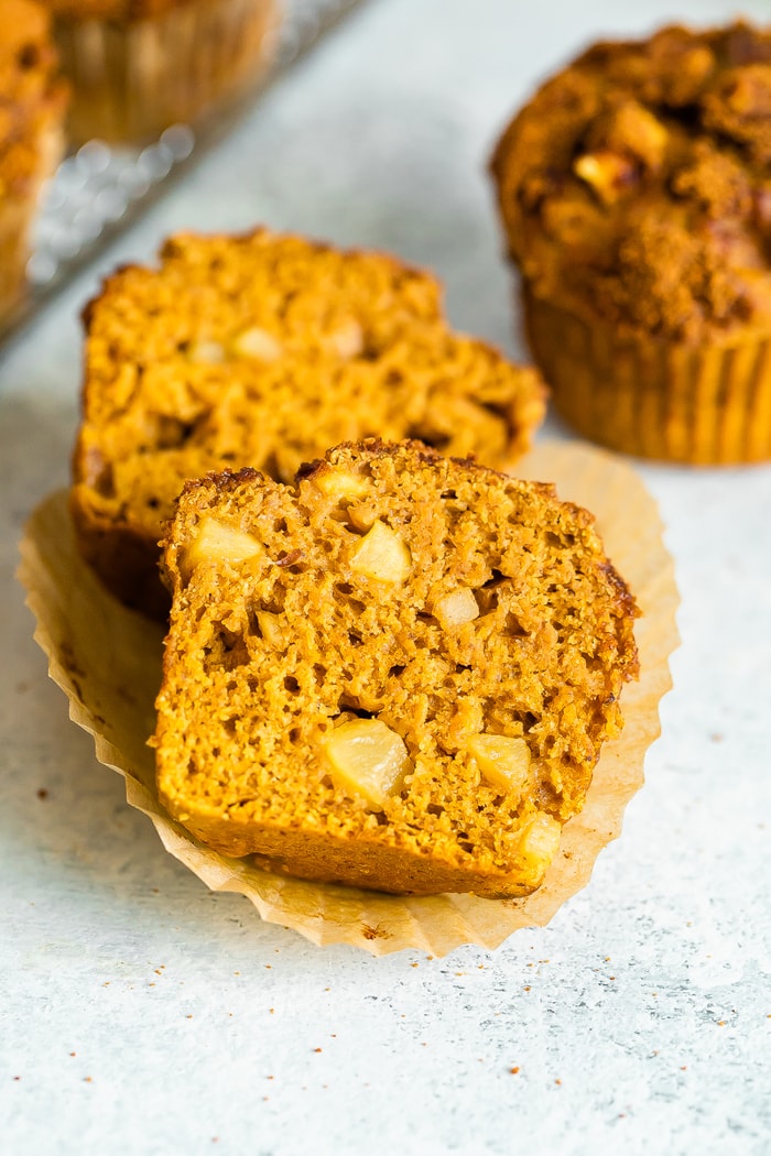 A healthy apple muffin cut in half. Muffin is full of apple chunks.