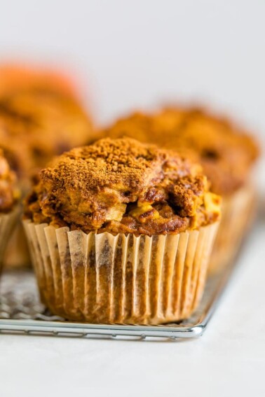 An apple cinnamon muffin sitting on a cooling rack.