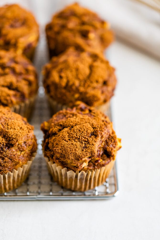 Apple muffins topped with cinnamon sugar on a cooling rack.