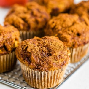 Apple muffins topped with cinnamon sugar on a cooling rack.