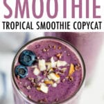 A purple health nut smoothie topped with blueberries, chopped almonds, and cacao nibs.