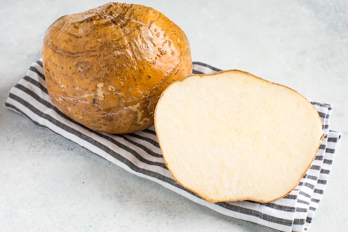 Jicama cut in half on a gray and white striped towel.