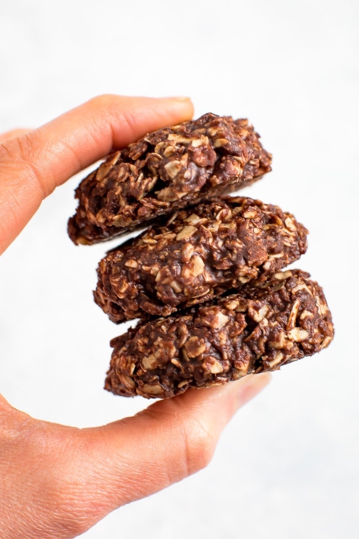 Hand holding a stack of three peanut butter chocolate healthy no bake cookies.