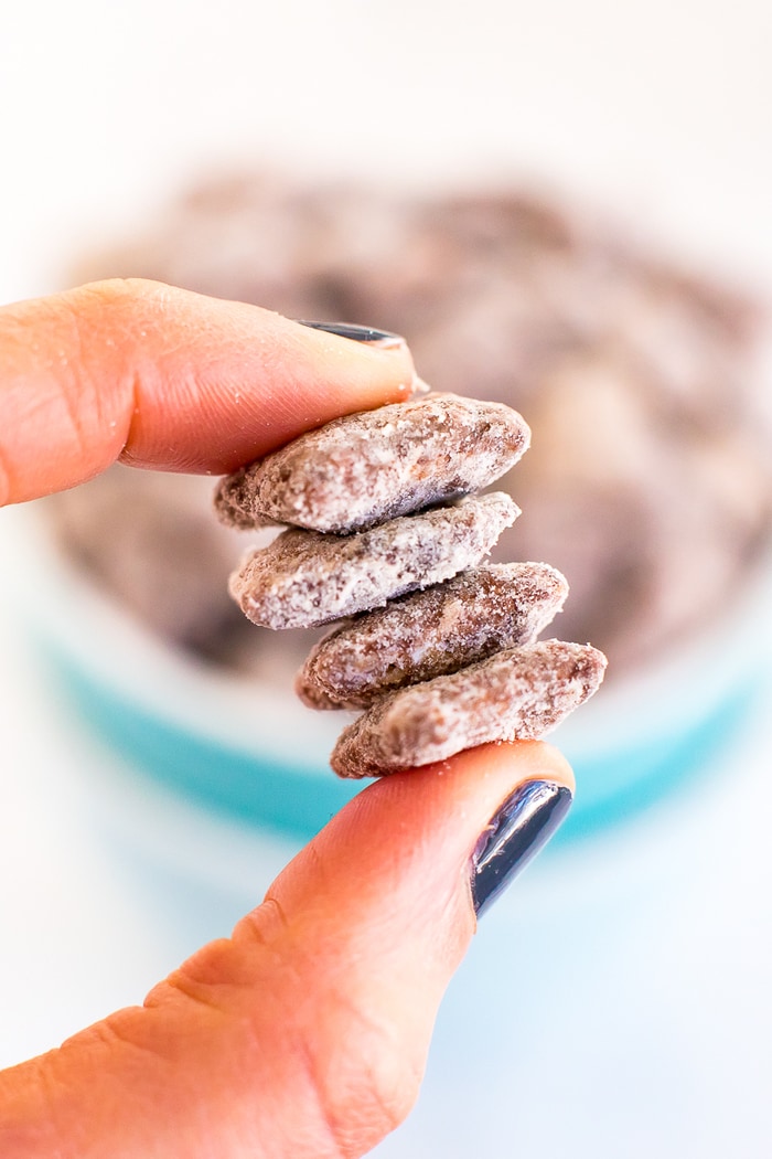 A hand holding four pieces of protein muddy buddy mix.