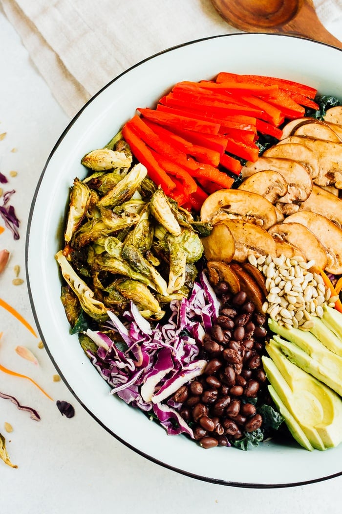 Close up overhead shot of large salad bowl with ingredients spread around bowl. 