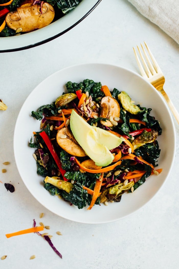 Overhead shot of single serving of detox kale salad with sliced avocado on top. 