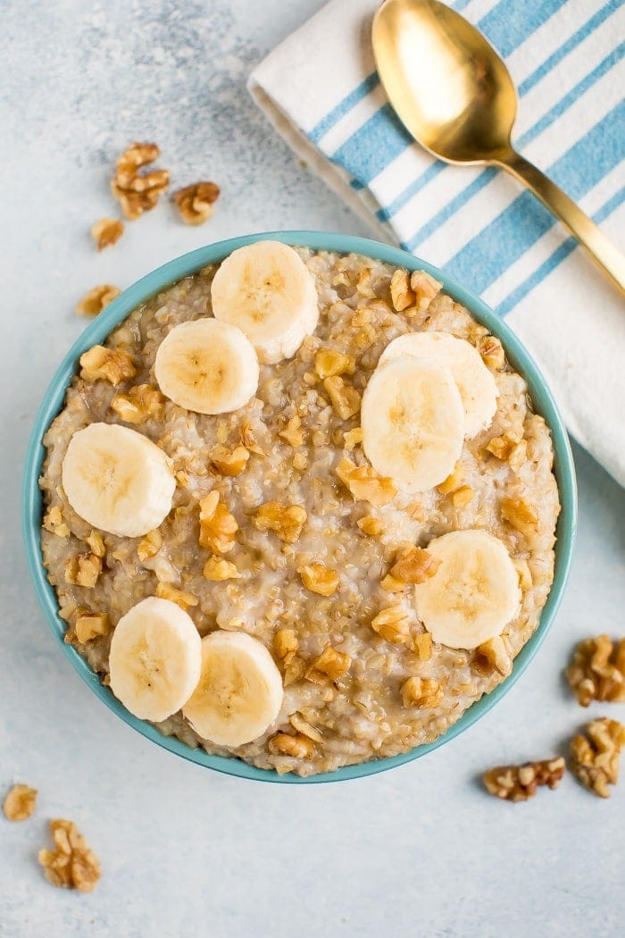 Overhead shot of creamy steel cut oats topped with banana slices and walnuts in a blue bowl. 