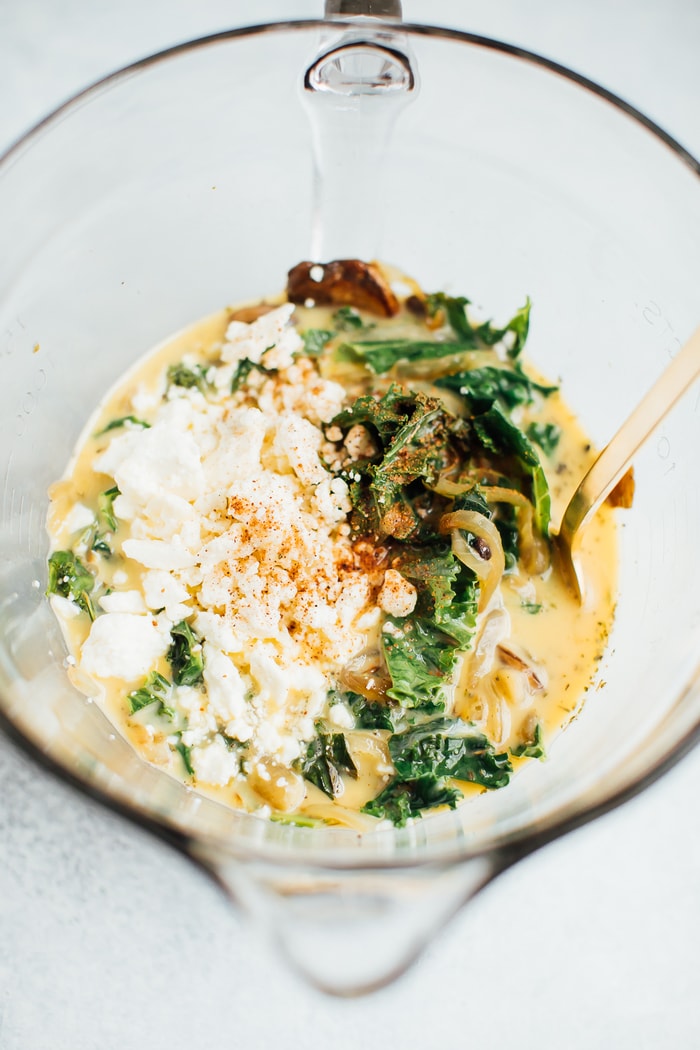 All the ingredient for crustless quiche in a clear glass mixing bowl.