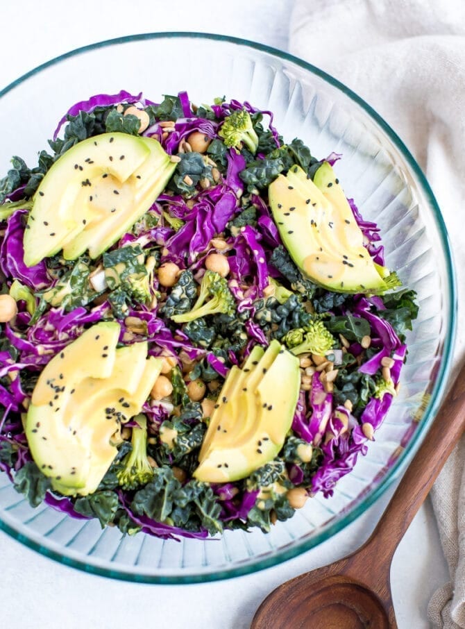 Salad with kale, cabbage, avocado, broccoli, chickpeas, and a nutritional yeast goddess dressing in a bowl.