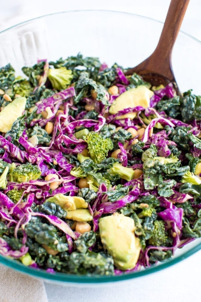 Salad with kale, cabbage, avocado, broccoli, chickpeas, and a nutritional yeast goddess dressing in a bowl.