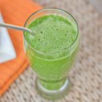 Green lemonade smoothie in a tall glass with a straw.