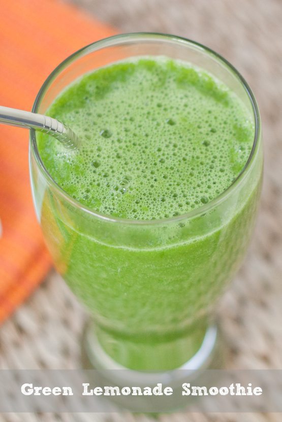 Green lemonade smoothie in a tall glass with a straw.
