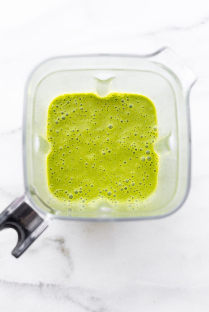 Overhead view of blender container filled with a green smoothie.