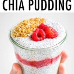 Hand holding a jar of raspberry cheesecake chis pudding layered with raspberries and topped with granola and raspberries.