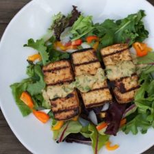 Overhead photo of a plate with lemon basil tofu on a bed of mixed greens.