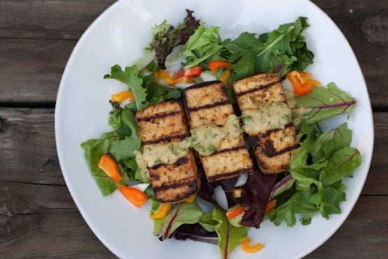 Overhead photo of a plate with lemon basil tofu on a bed of mixed greens.