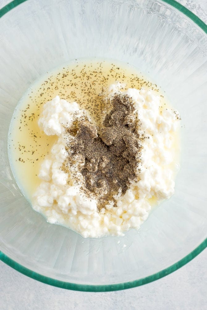 Cottage cheese and egg whites with spices in a bowl for the healthier ricotta filling.