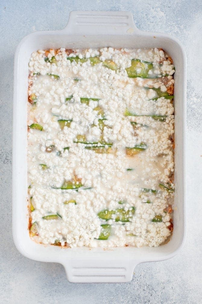 Baking pan layered with tofu meat sauce, zucchini noodles and marinara sauce.