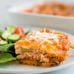 Slice of zucchini noodle tofu lasagna on a plate with salad.