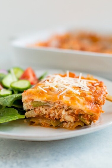 Slice of zucchini noodle tofu lasagna on a plate with salad.