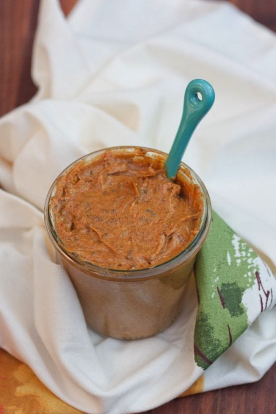 A fall spin on your favorite nut butter, this pumpkin almond butter combines roasted almonds, pumpkin puree and spices to make a delicious spread you'll want to put on everything! A jar of pumpkin almond butter sitting on a dish towel.