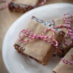 A no bake cookie bar square wrapped in brown parchment paper and tied with a red and white ribbon.