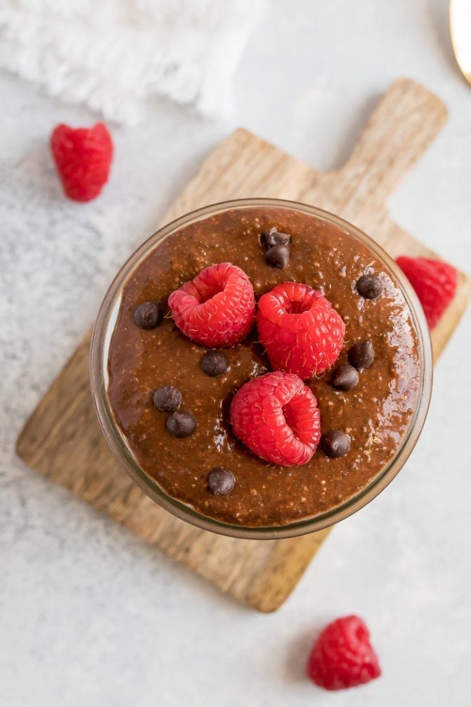 Bird's eye view of a jar of chocolate chia pudding, topped with chocolate chips and raspberries.